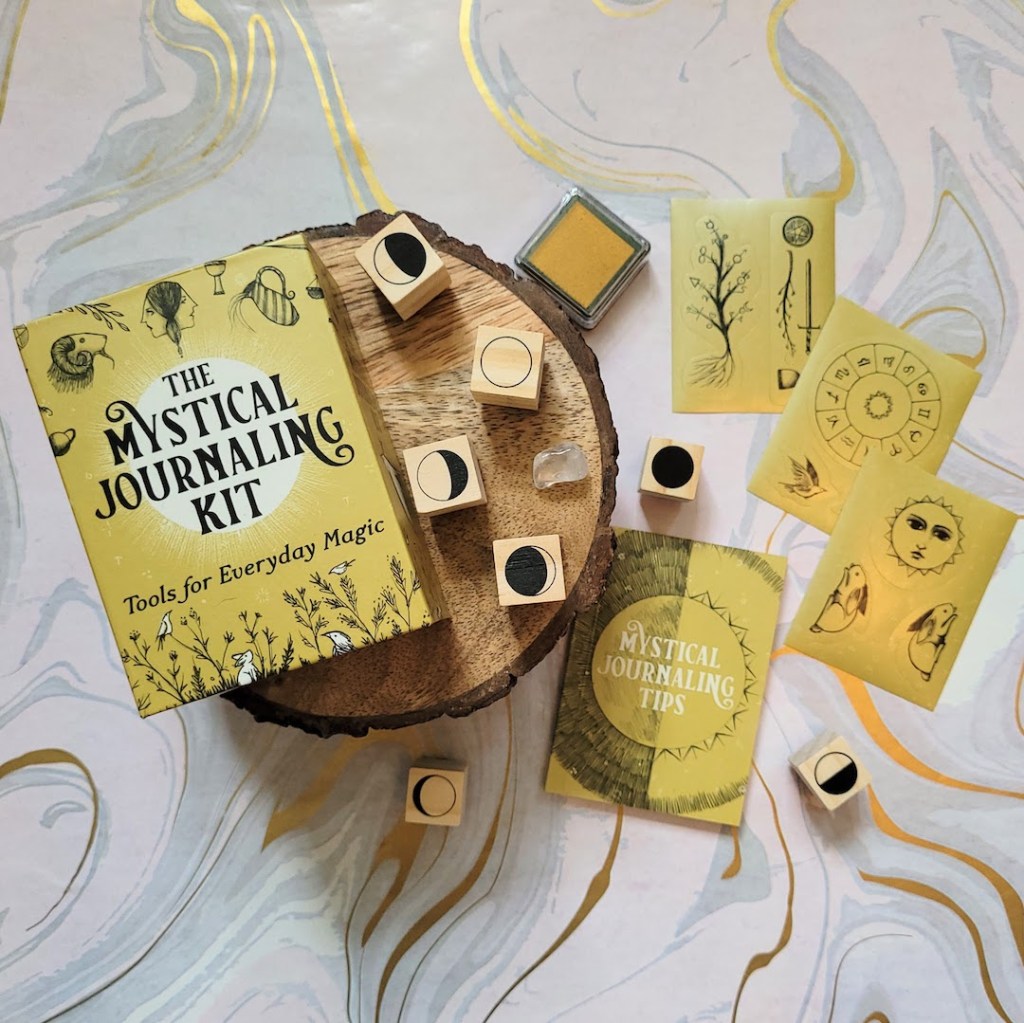 Photo of the "Mystical Journaling Kit" box and components laid out against a marbled background