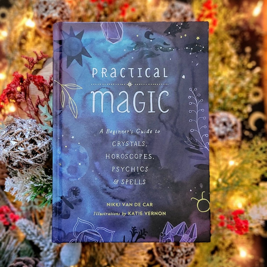 Photo of "Practical Magic" laid above wintry decor and soft holiday lights