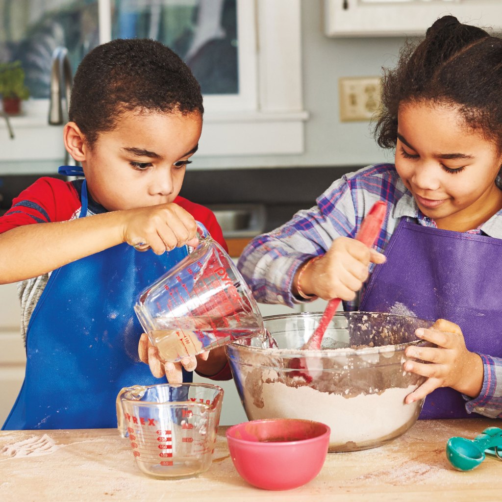 Photo of kids pouring ingredients into a bowl.