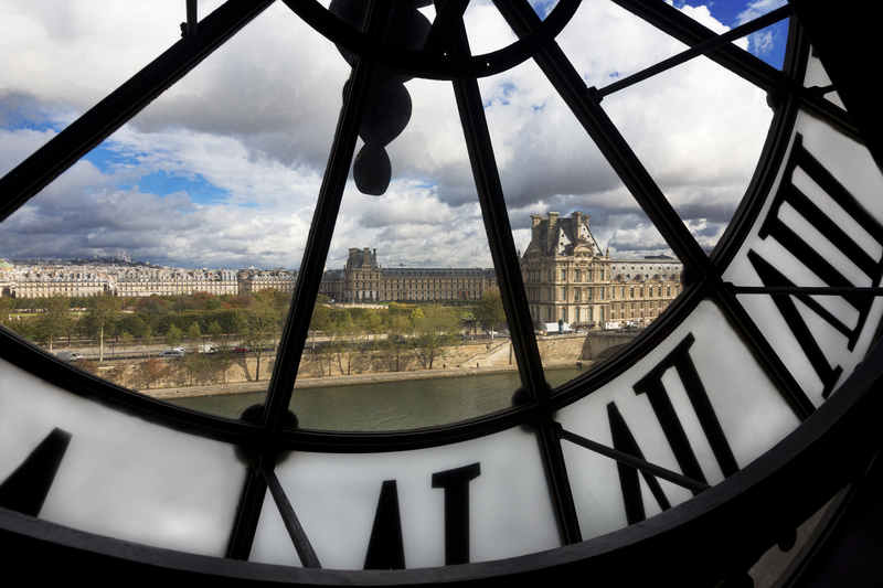 Image of river and beautiful stone building as seen through a giant clock face.