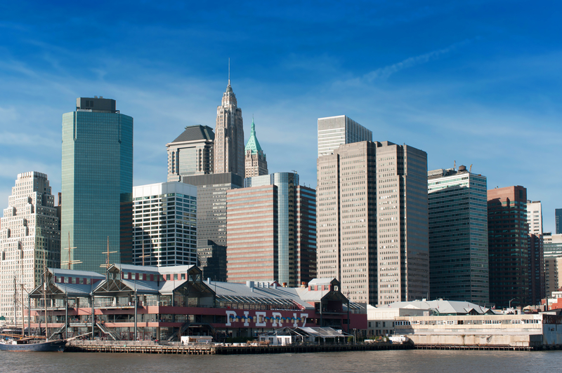 Image of pier and city skyline under bright blue sky.