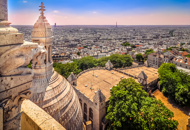 View of Paris from a church tower with part of the white towers of Sacre-Coeur visible.