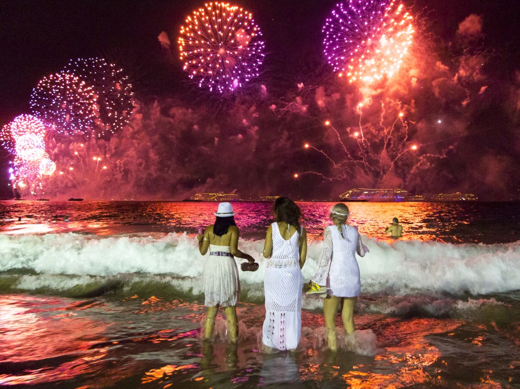 Three young women watching the fireworks in Rio de Janeiro from the beach on New Years Eve