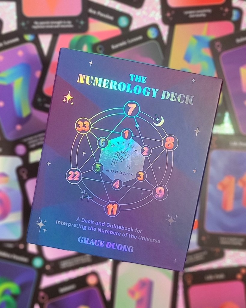 Photo of the box of Mystic Mondays: The Numerology Deck laid above face up cards from the deck.