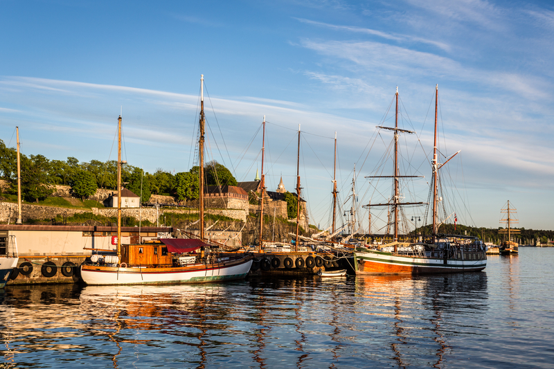 Boats in harbor with stone fortress in background at sunset