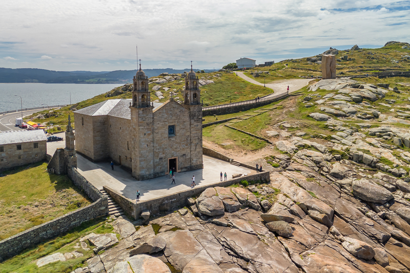 Aerial image of a large stone church on a rocky peninsula next to the sea