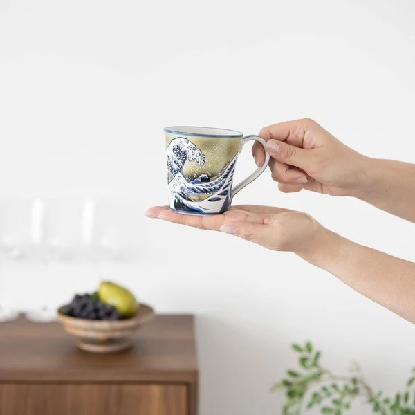 Hand holding mug with wave on it
