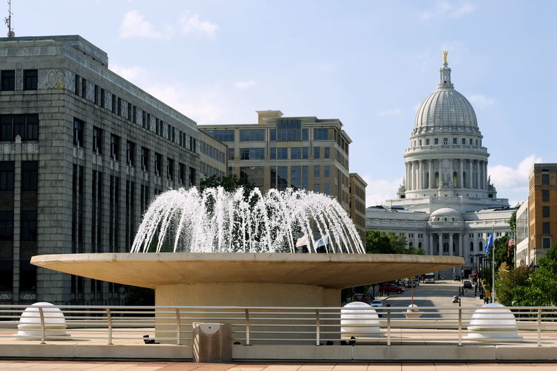 a bubbling stone fountain with a view of the domed capital building behind it
