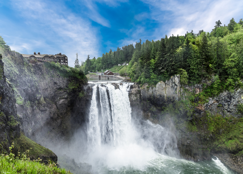 A large waterfall tumbling over a rocky canyon into mist with evergreen forest on either side