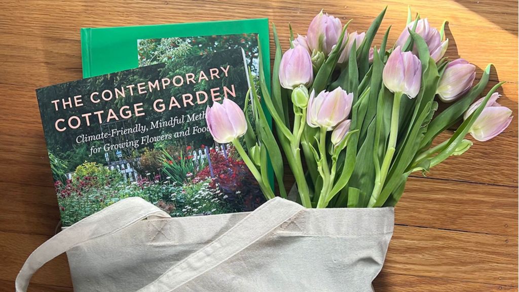 Two gardening books and a bouquet of tulips in a canvas farmers market tote bag