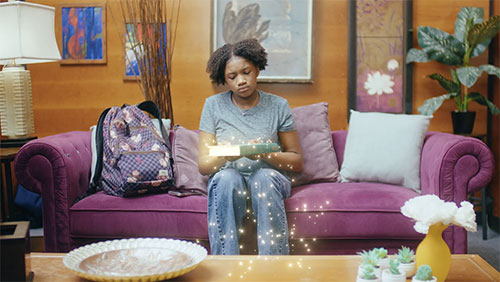 Image of young girl sitting on a couch with a book.