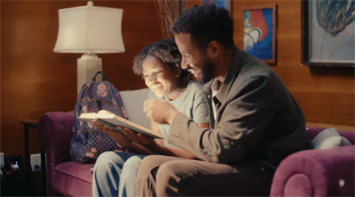 Image of young girl sitting on a couch with a book.