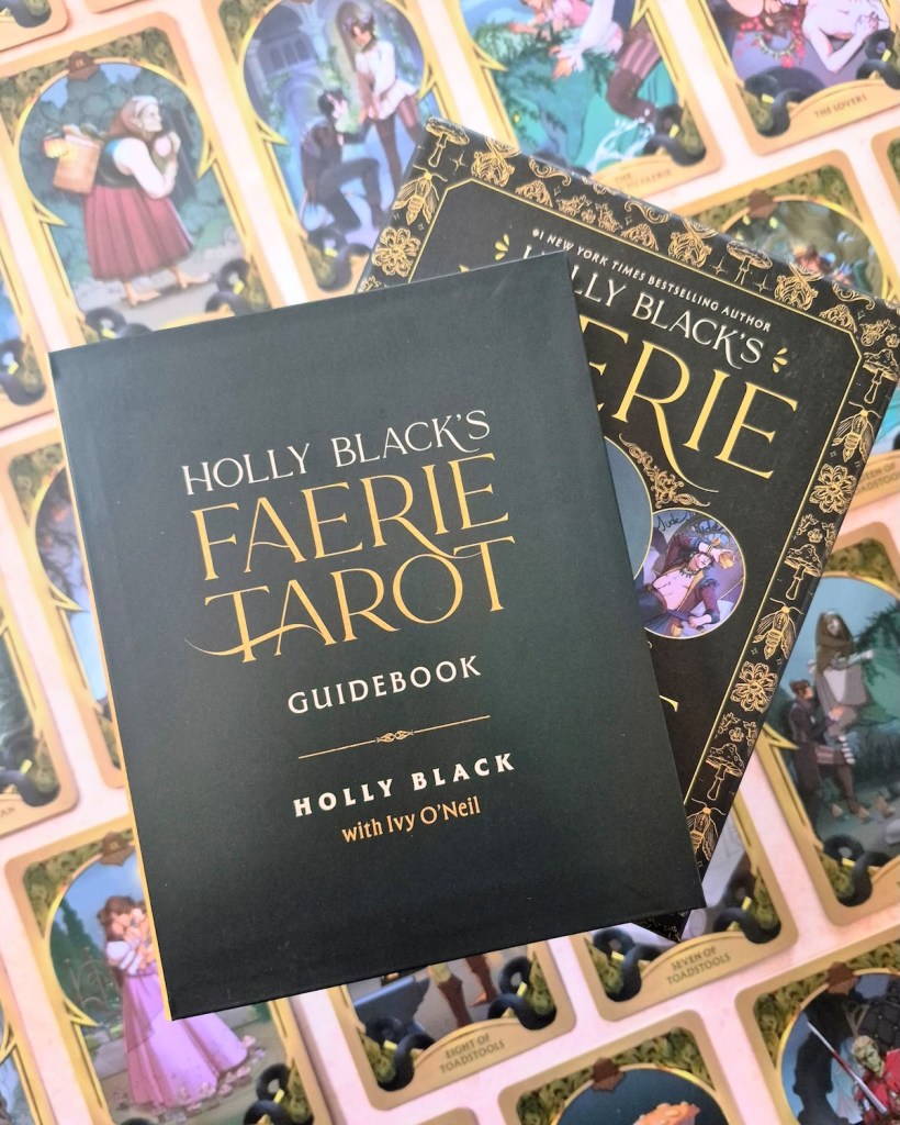 Photo of the guidebook and box of Holly Black's Faerie Tarot laid above cards from the deck