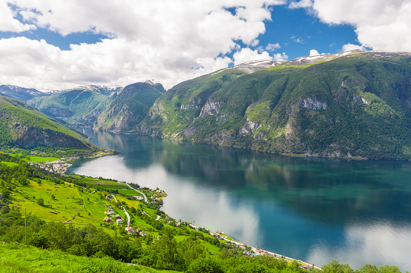View of fjord landscape with small houses and villages on lush green hills