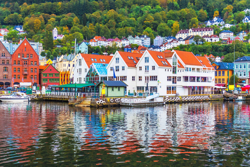 Colorful houses on a pier reflected in the water with green trees in the background