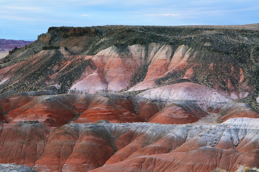 buttes in a desert landscape that are layered with different colors, appearing as if they're painted