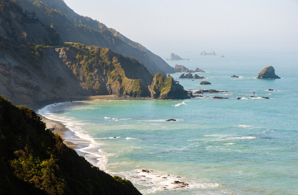Cliffs descend into a blue and green ocean, dotted with rocks