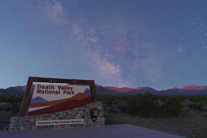 Sign at the entrance of Death Valley National Park with a nighttime sky above it