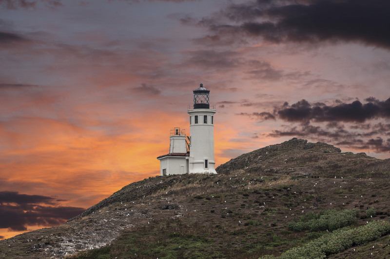 Lighthouse on a hill at sunset